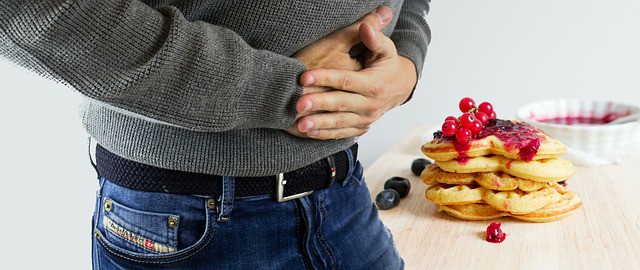 man next to food holding belly