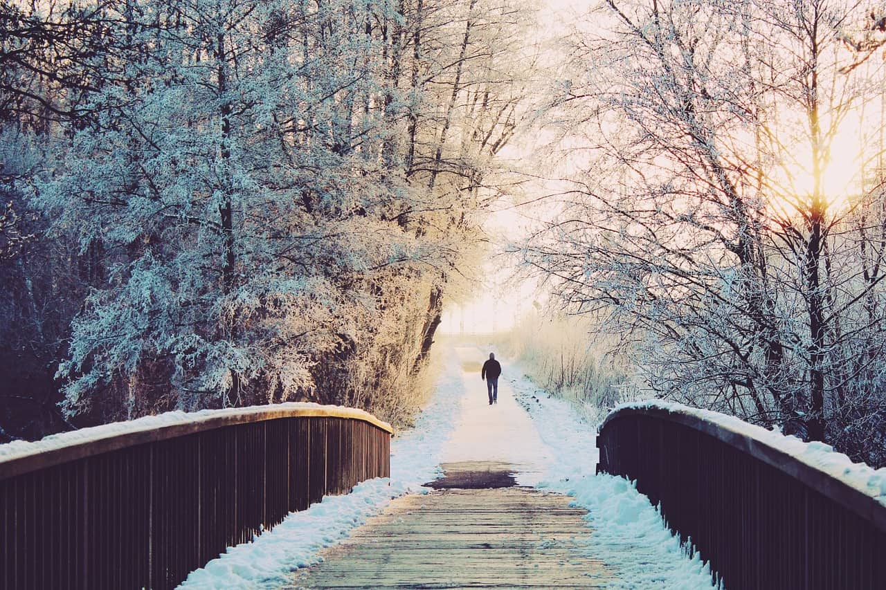 man walking on bridge in snow