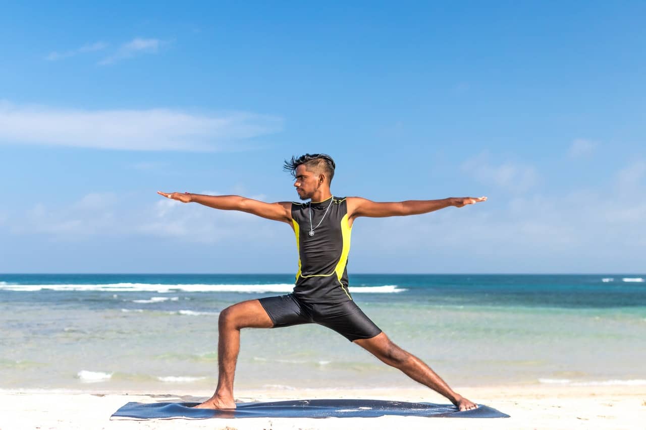 man doing yoga on beach